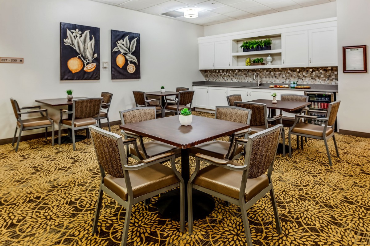 A modern dining area with neatly arranged tables and chairs, featuring artwork on the walls.