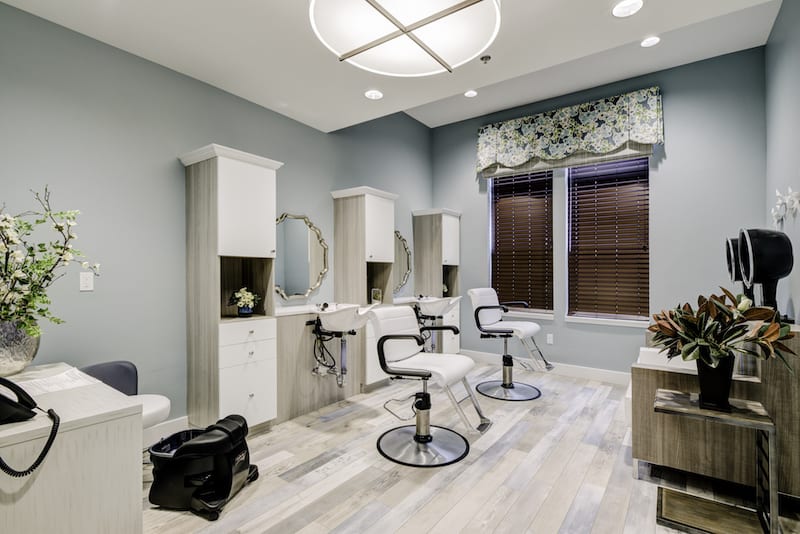 A modern hair salon interior with stylish chairs and mirrors.