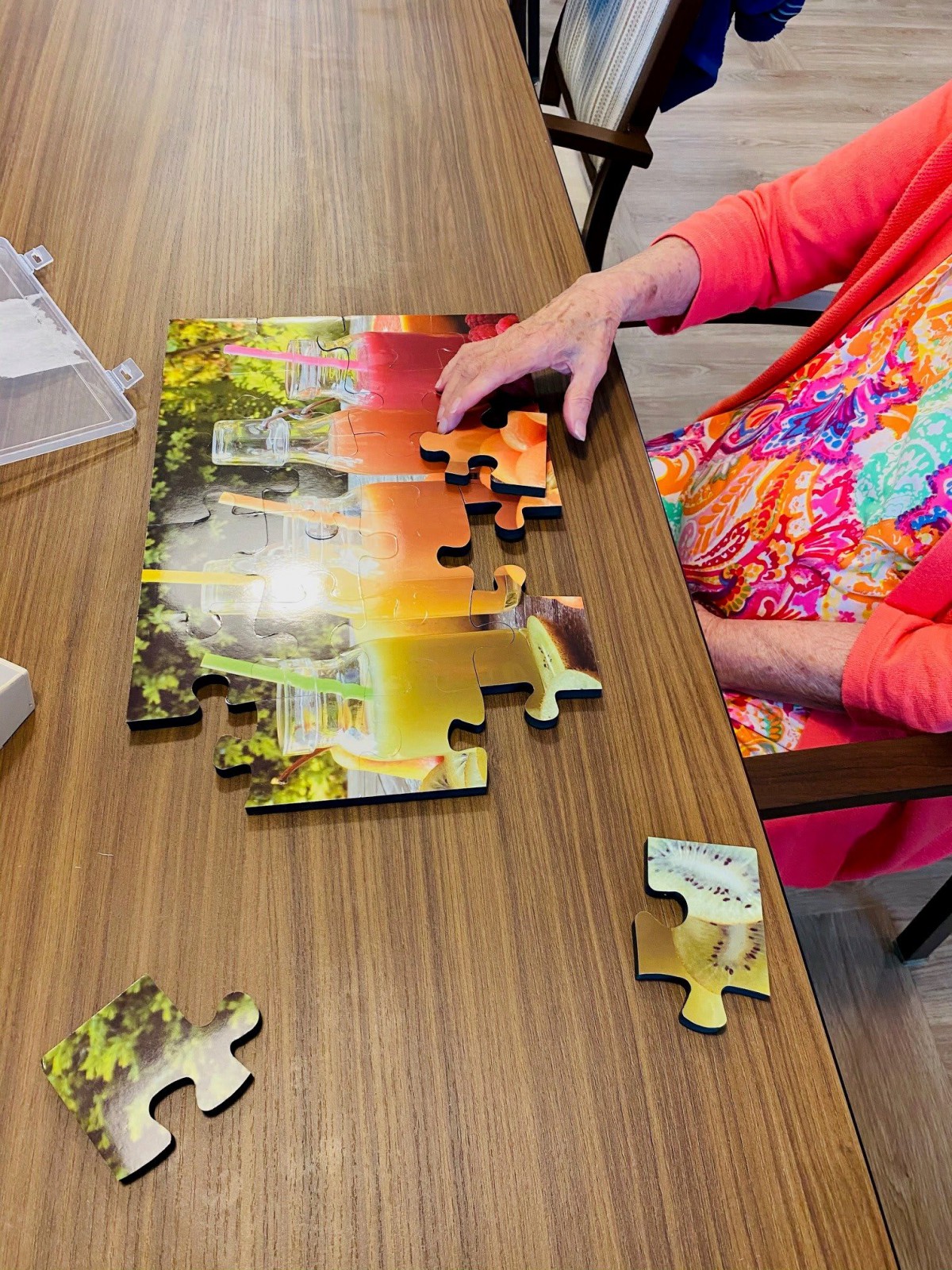 A person works on assembling a colorful jigsaw puzzle at a table.