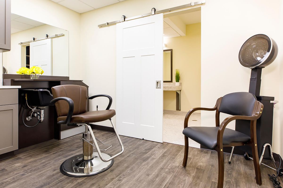 A tidy and well-lit salon interior with chairs and a mirror.