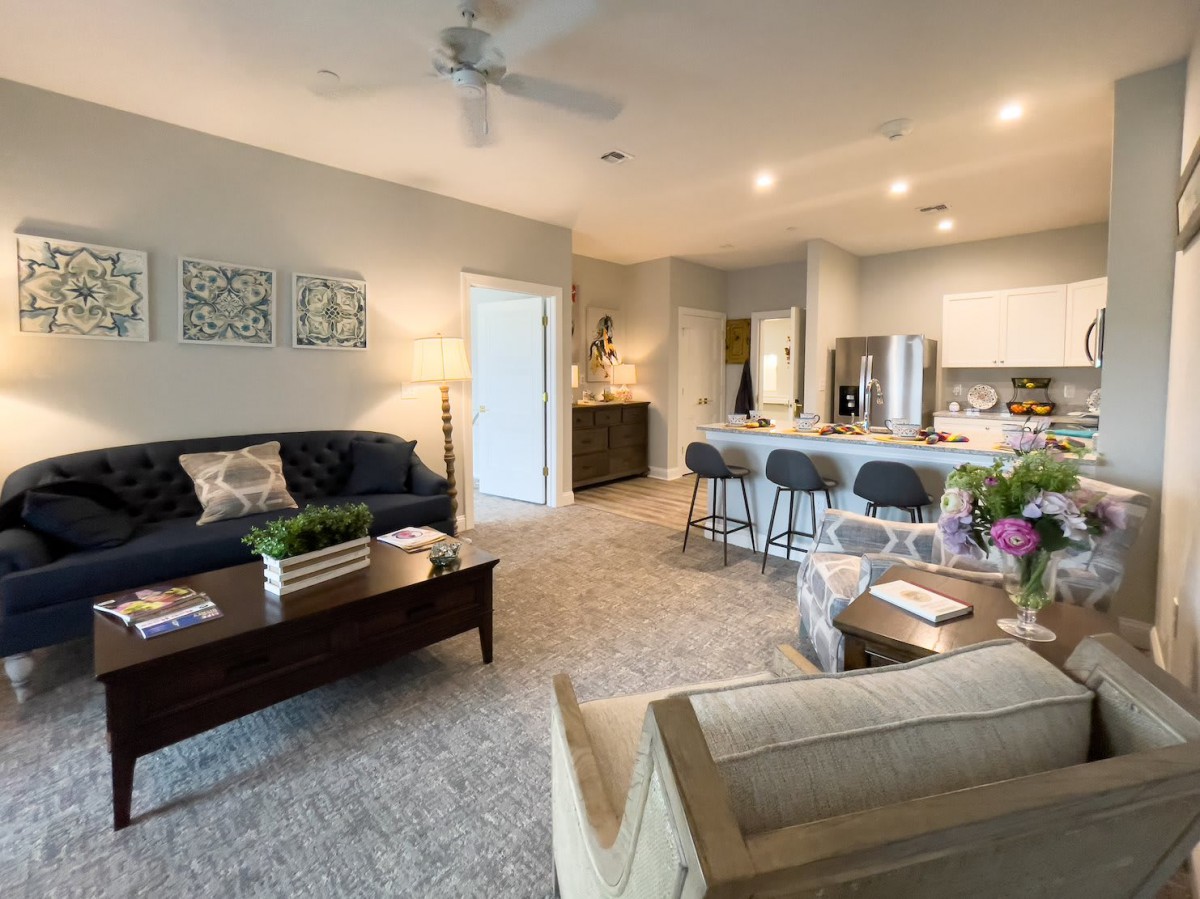 A modern living room with an open kitchen, featuring stylish furniture and contemporary decor.