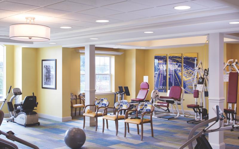 A well-lit exercise and rehabilitation room with gym equipment and seating.