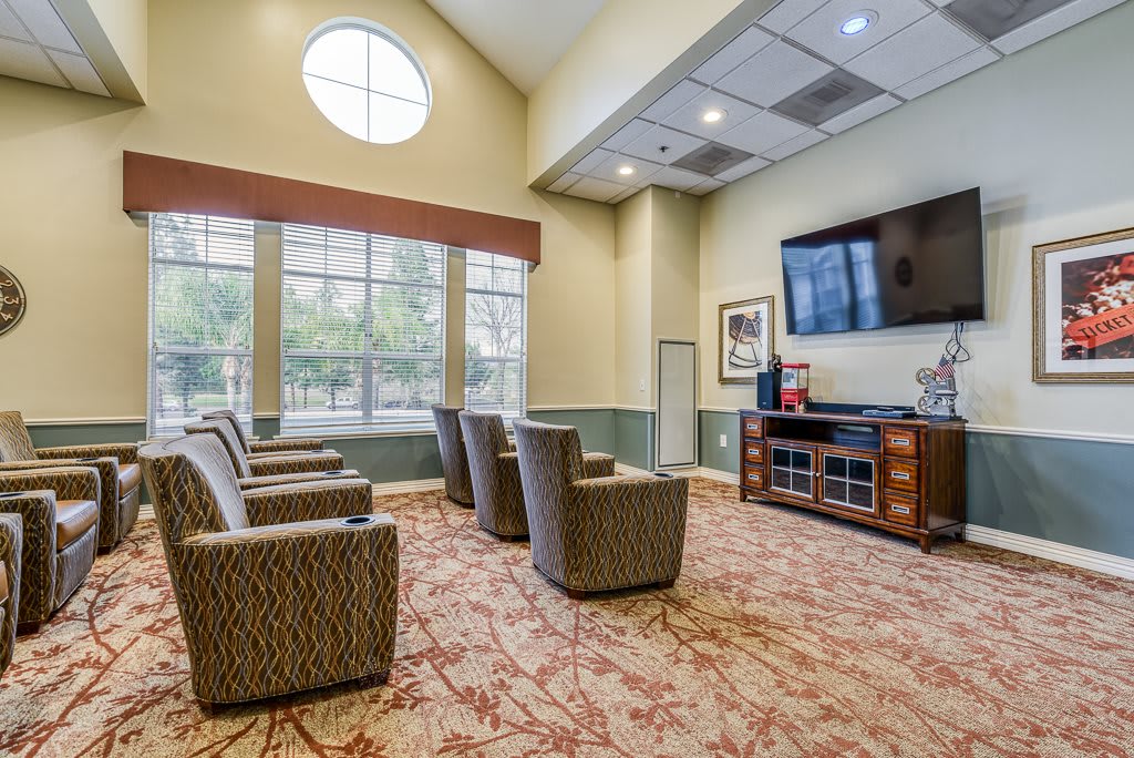 A spacious lobby with comfortable seating and a large television, illuminated by natural light from multiple windows.
