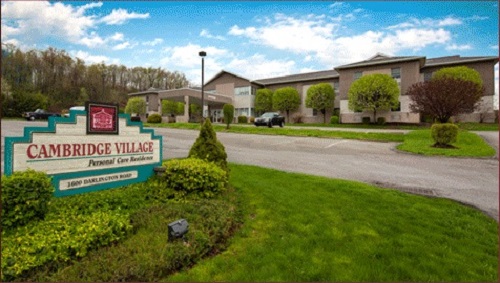 A welcoming entrance to a charming village, surrounded by lush greenery and a bright blue sky.