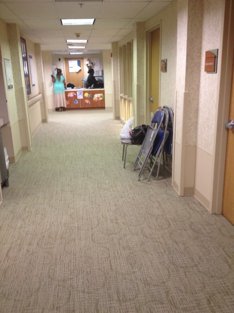 A hospital corridor with chairs stacked against the wall and a reception desk in the distance.