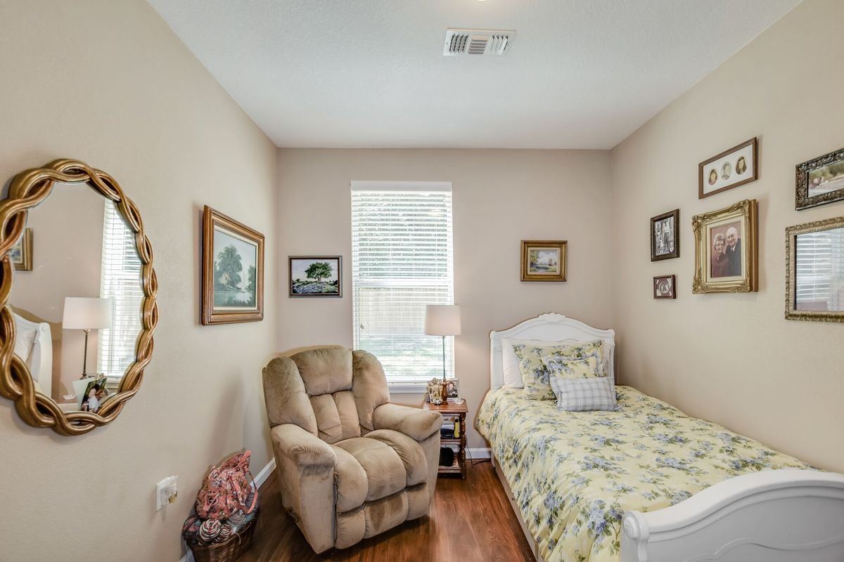 A cozy bedroom with a single bed, armchair, and decorative wall art.