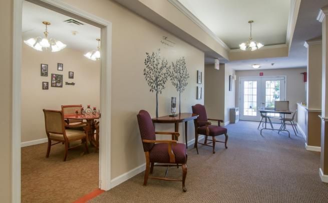 A well-lit hallway featuring elegant chairs and decorative wall art.