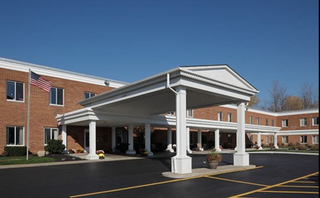 A commercial building with a grand entrance featuring columns and a paved parking area.