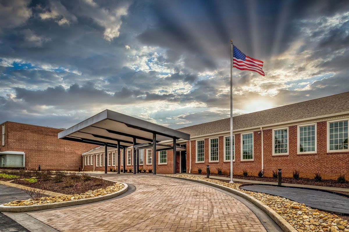 A brick building with an American flag flying outside under a cloudy sky.
