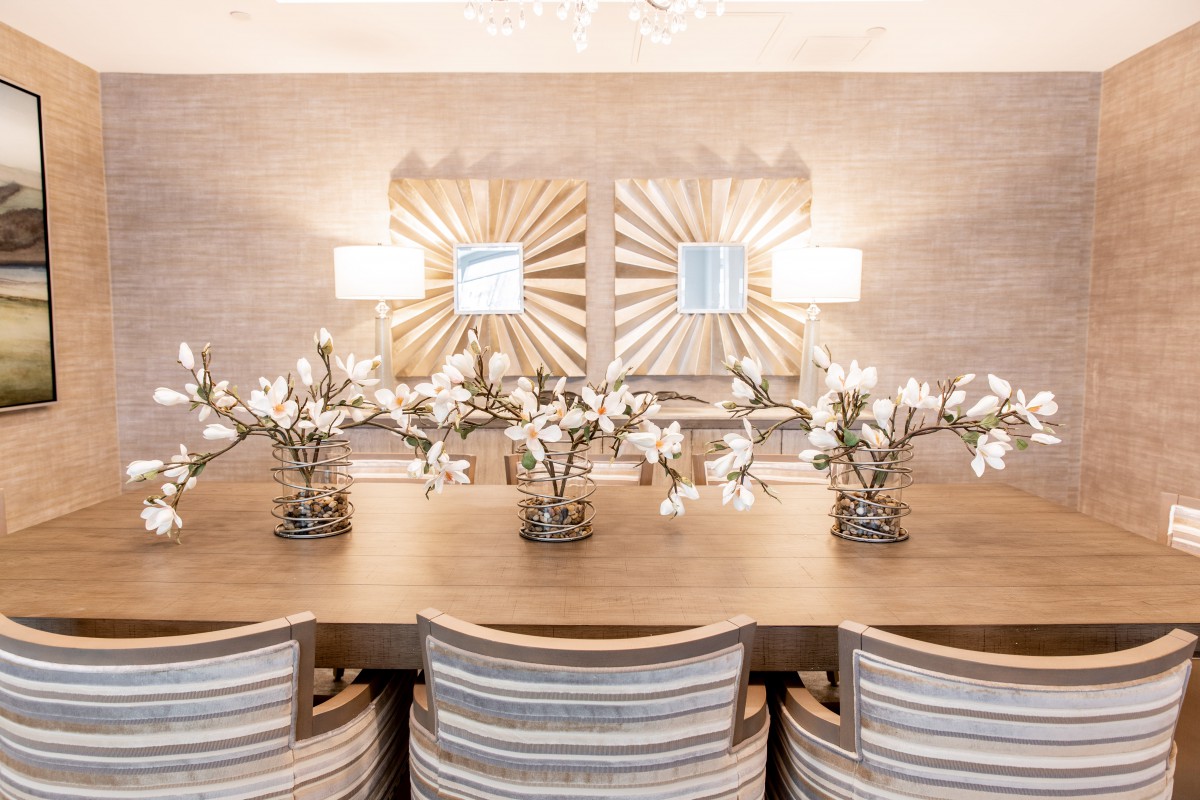A stylish dining room setup with a large table, elegant decor, and floral arrangements.