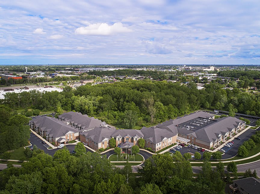 Aerial view of a residential area surrounded by trees under a cloudy sky.