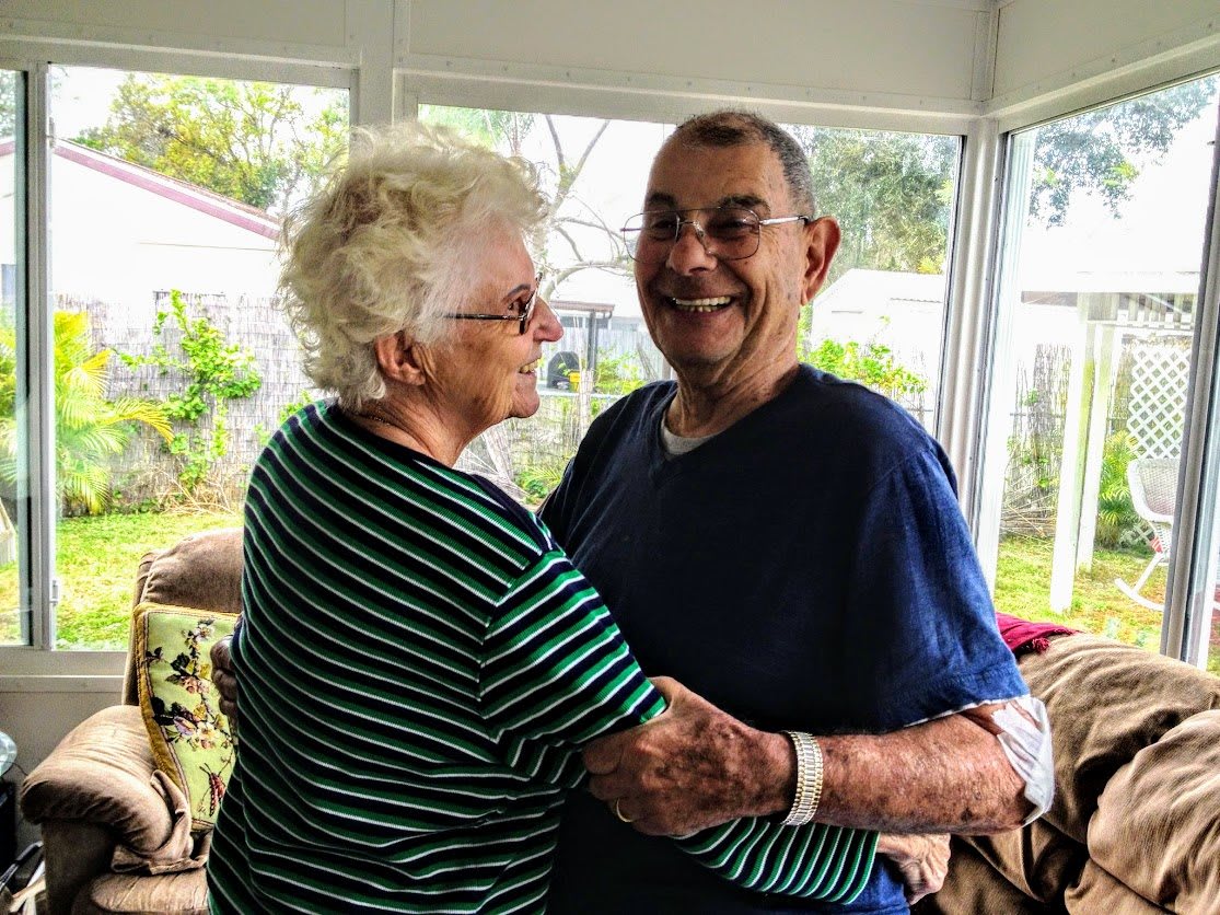 A joyful elderly couple dancing together at home.
