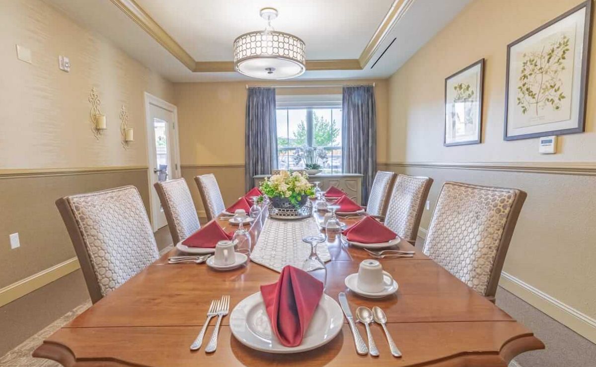 An elegantly set dining table with red napkins and a floral centerpiece.