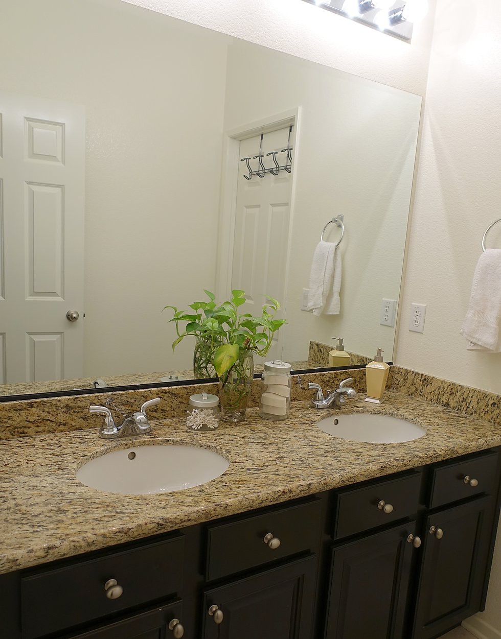 A well-organized bathroom with a granite countertop and double sinks.