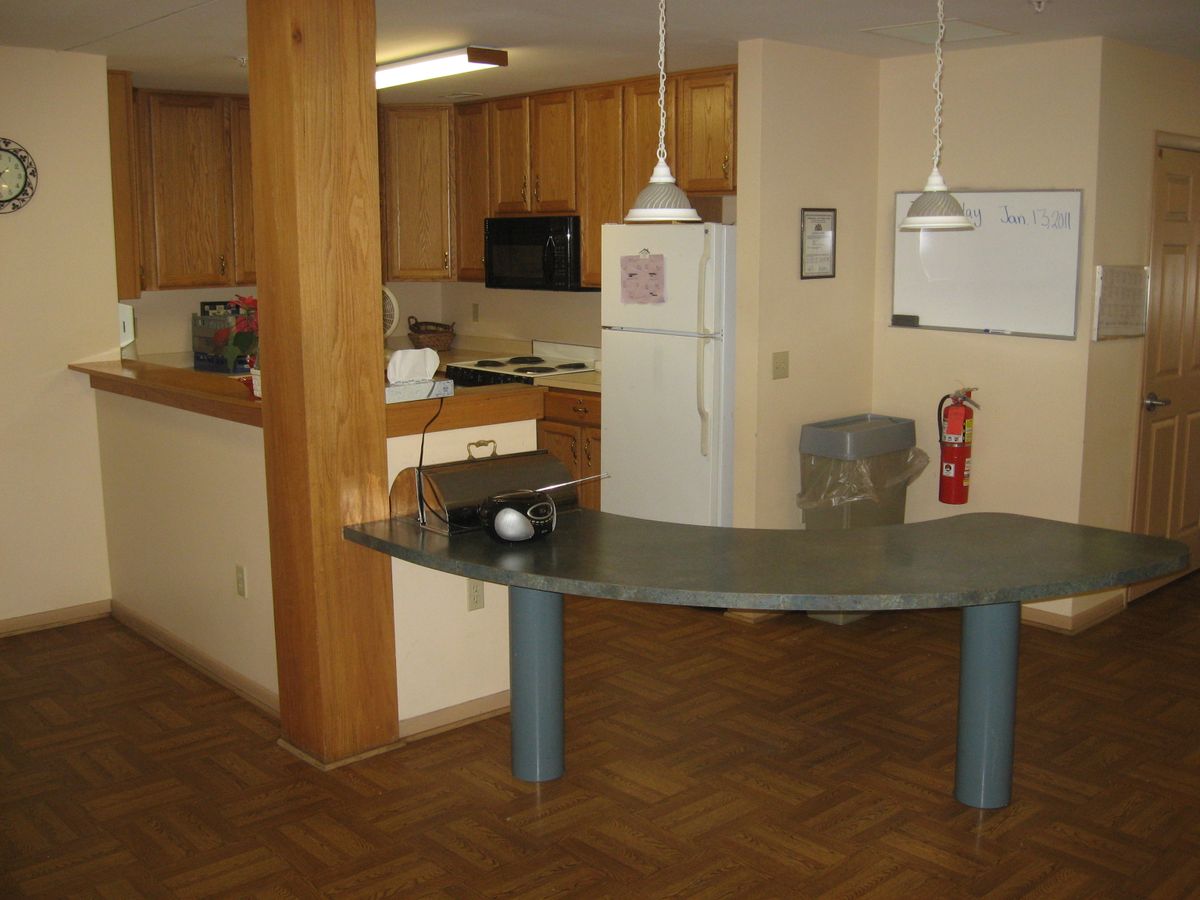 A modern kitchen with wooden cabinets and a curved countertop in an open apartment layout.