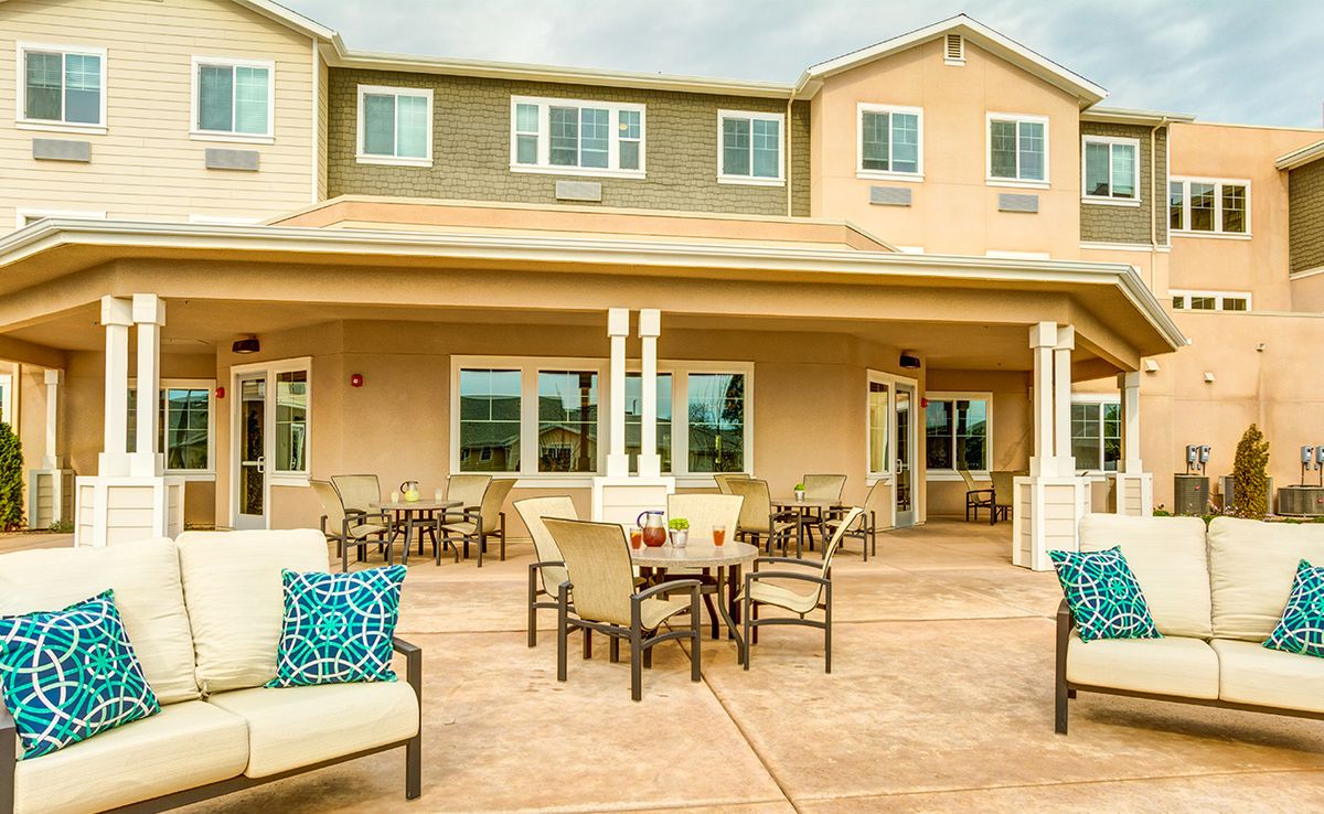 A spacious outdoor patio area with comfortable seating in front of a large house.