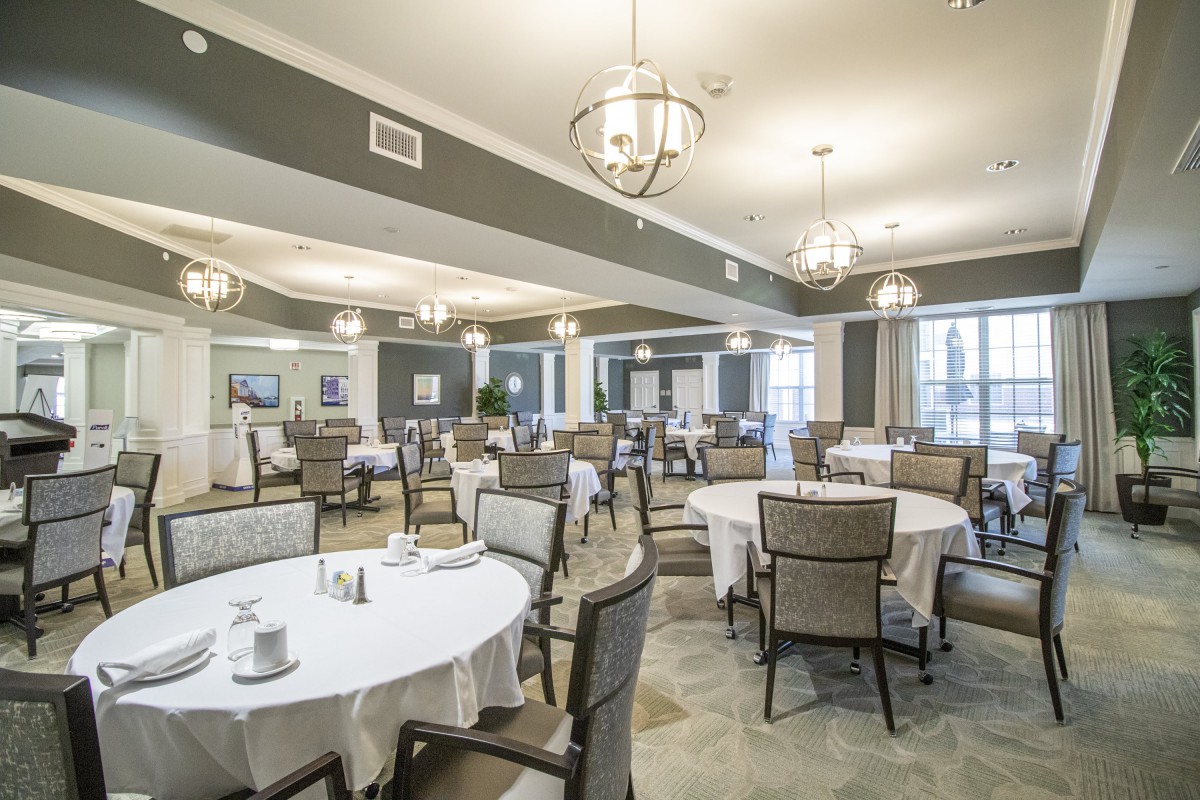 An elegant dining room with round tables and chandeliers.
