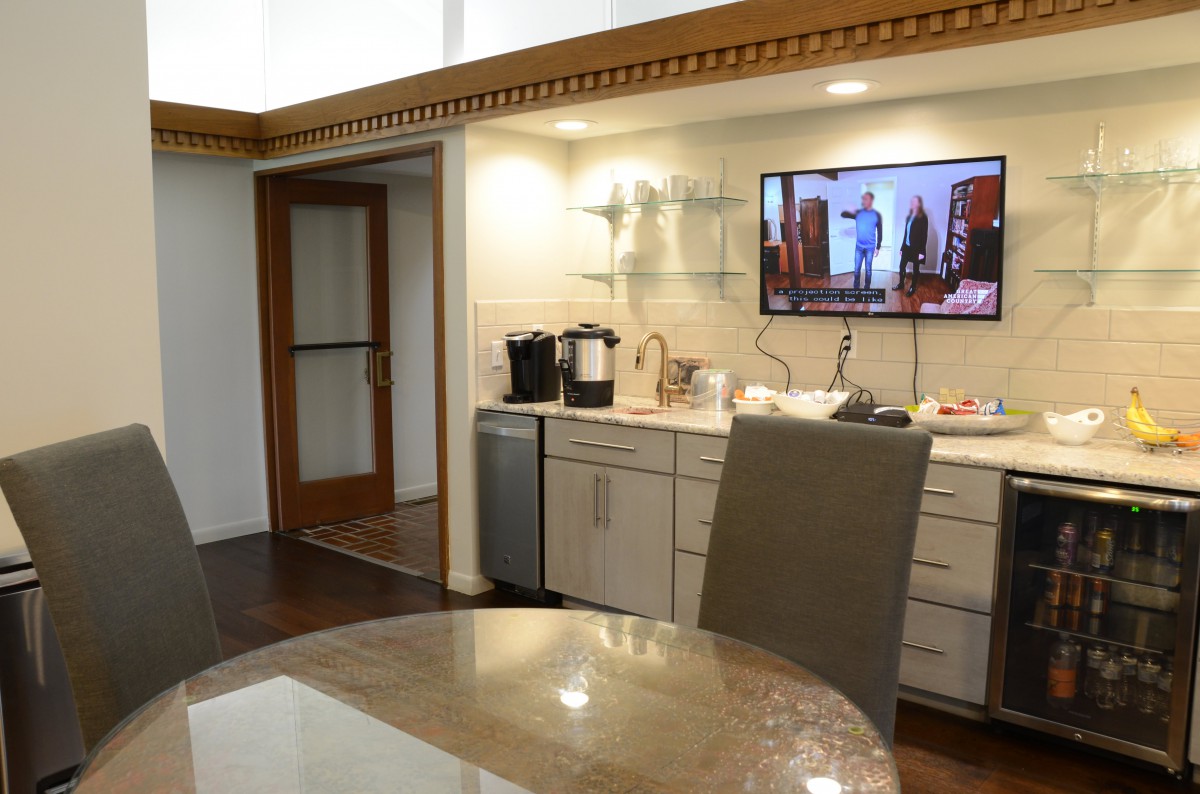A modern kitchen interior featuring a coffee maker and a mounted television.