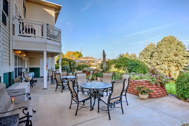 Spacious outdoor patio with tables and chairs overlooking a lush garden.