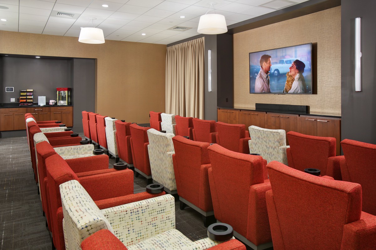 A cozy home theater with red seating and a large screen for movie viewing.