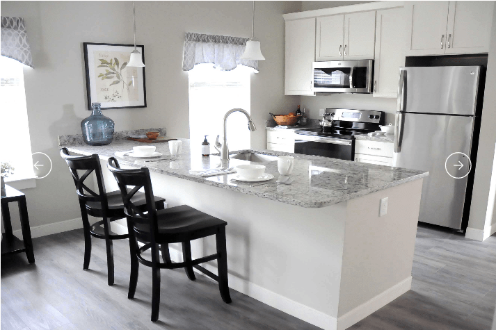 A modern kitchen with white cabinets, a marble countertop island, and stainless steel appliances.