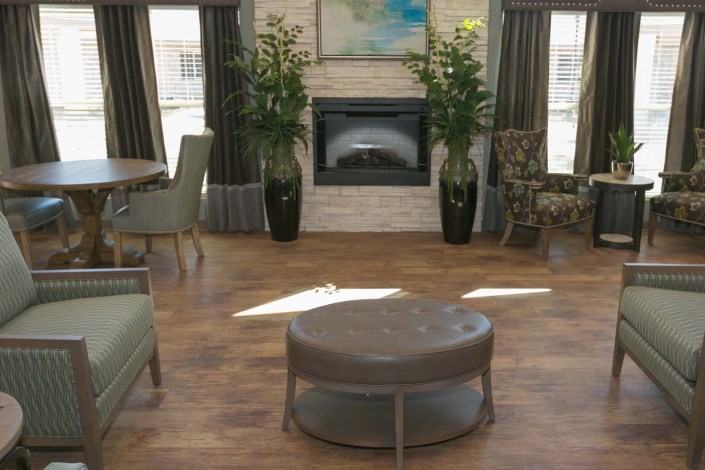 A cozy living room featuring a central fireplace, surrounded by plants and comfortable seating.