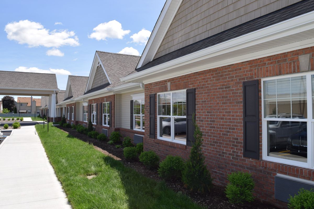 A row of single-story residential buildings with brick exteriors and well-maintained landscaping.