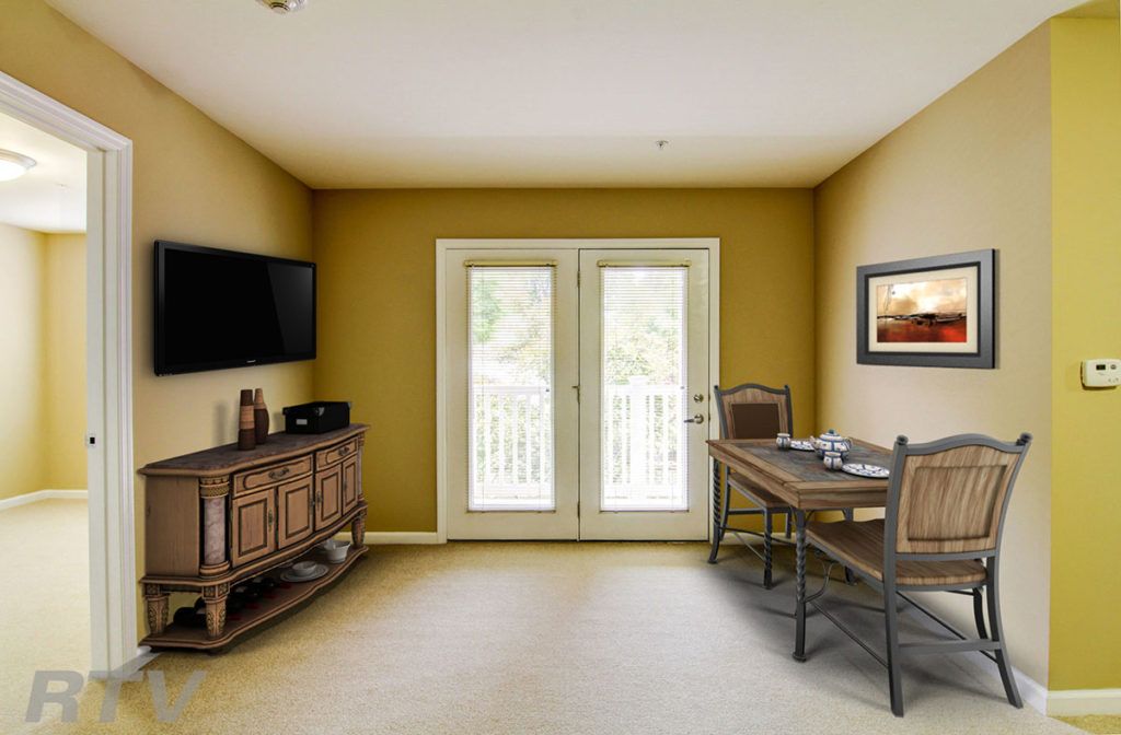 A cozy living room with a table and chairs, television mounted on the wall, and double doors leading outside.