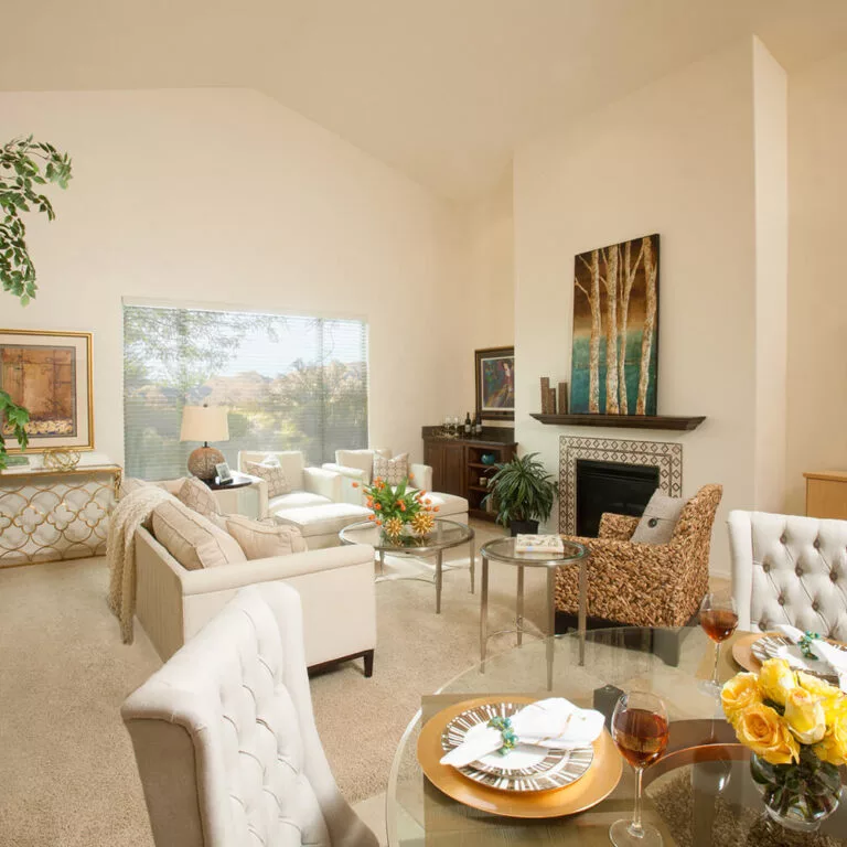 A cozy, well-decorated living room with neutral-toned furniture and a fireplace.