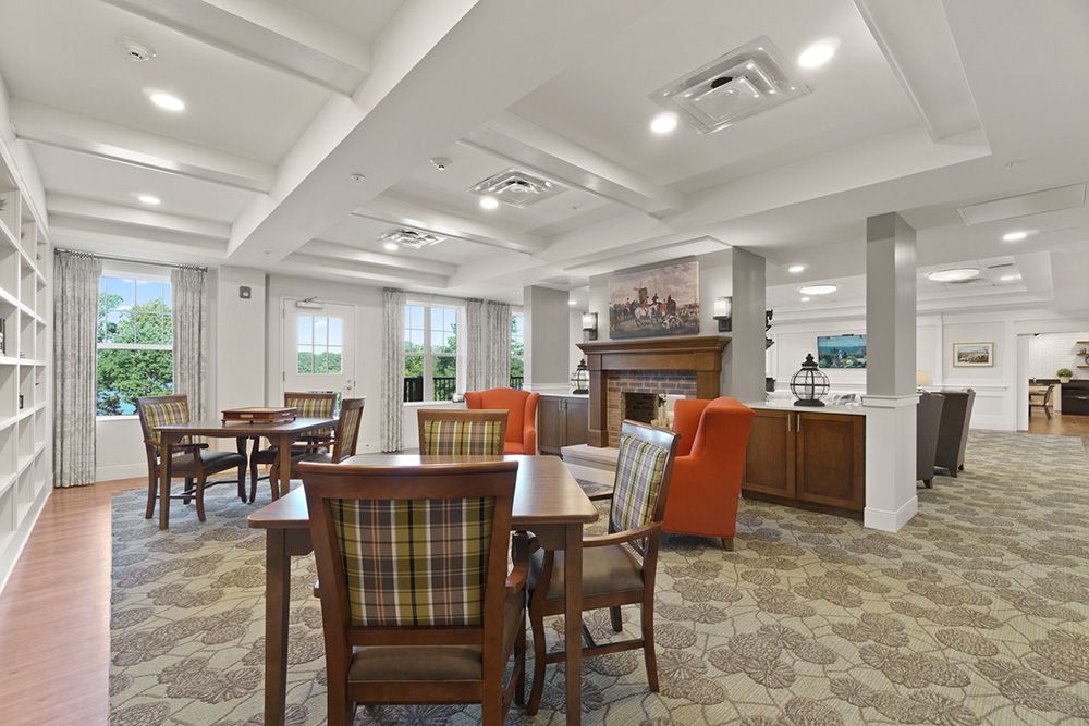 A cozy dining area with wooden tables and chairs, featuring a fireplace and modern lighting.