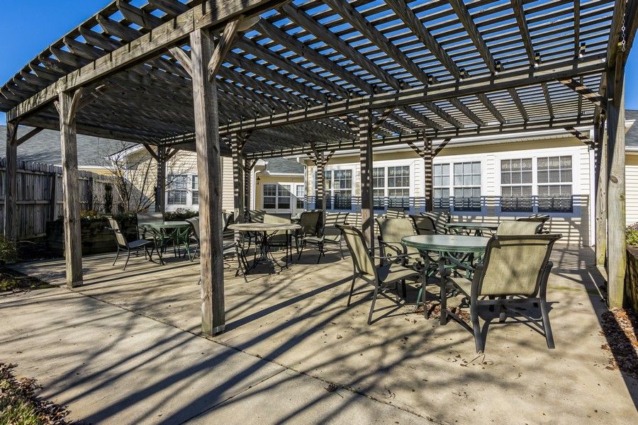 Outdoor patio area with a pergola providing shade over tables and chairs.