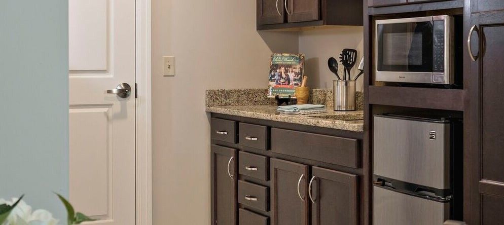 A modern kitchen with dark cabinets and a granite countertop, featuring utensils and a cookbook display.