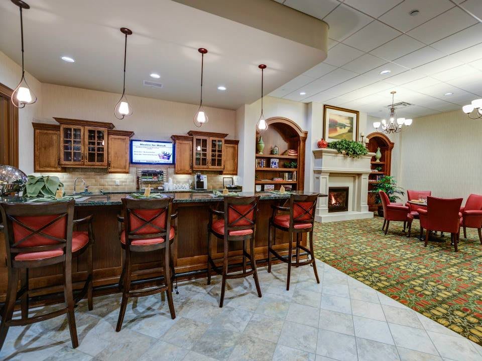 A cozy lounge area featuring a bar with wooden stools and a fireplace in the background.