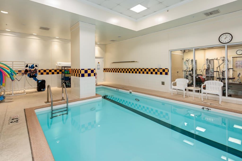 An indoor swimming pool adjacent to a fitness center, featuring clean and inviting facilities.