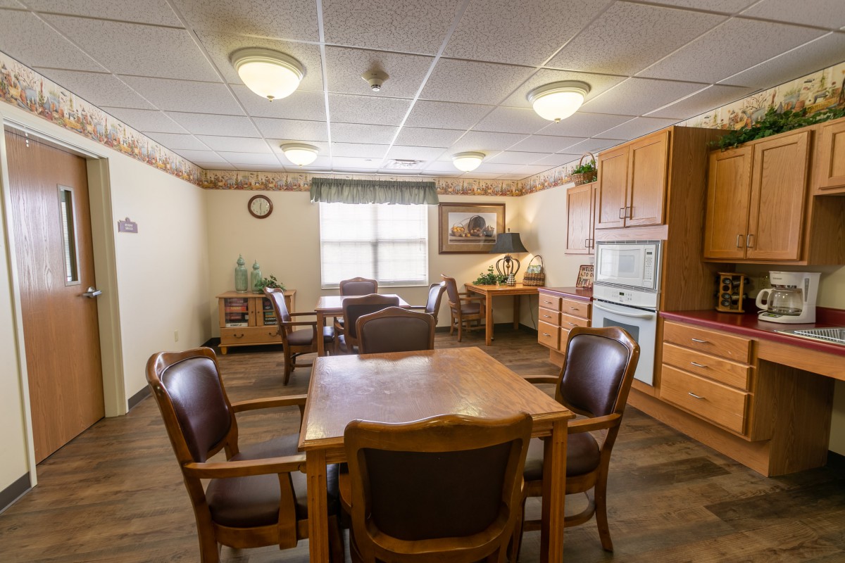 A cozy dining area with a wooden table and chairs, adjacent to a kitchen with wooden cabinets.