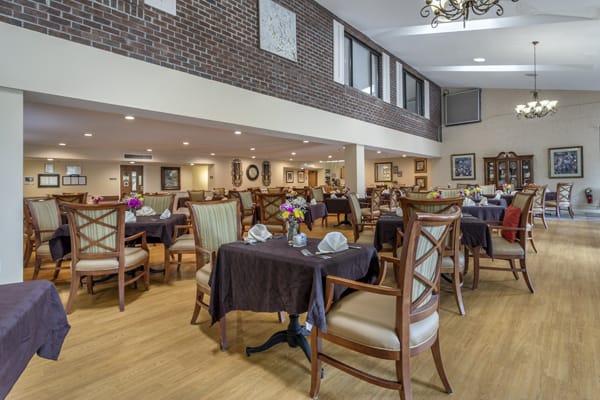 A spacious dining area with elegant tables and chairs, featuring modern decor and brick walls.