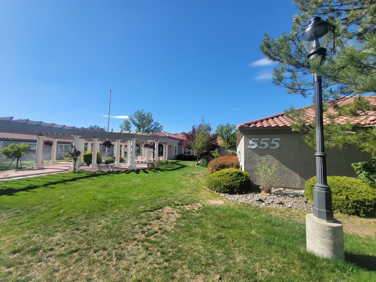 A sunny landscape featuring a building with manicured lawns and trees.