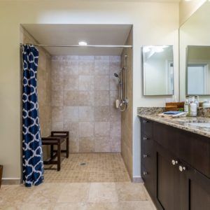 A modern bathroom with a tiled open shower and a dual-sink vanity.