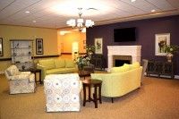 A cozy living room with light green sofas, a fireplace, and a TV on the wall.