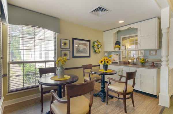 A cozy dining area with tables decorated with sunflowers and natural lighting.