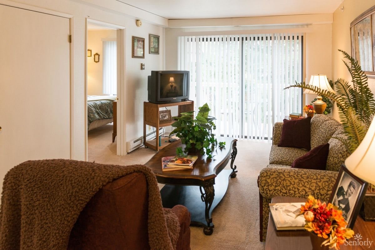 A cozy living room with a TV, coffee table, and sliding glass doors leading outside.