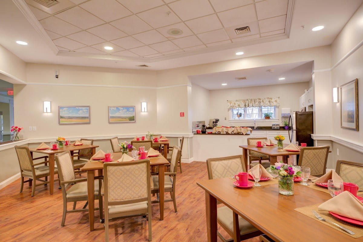 A cozy dining area with neatly arranged tables and chairs, featuring soft lighting and warm decor.