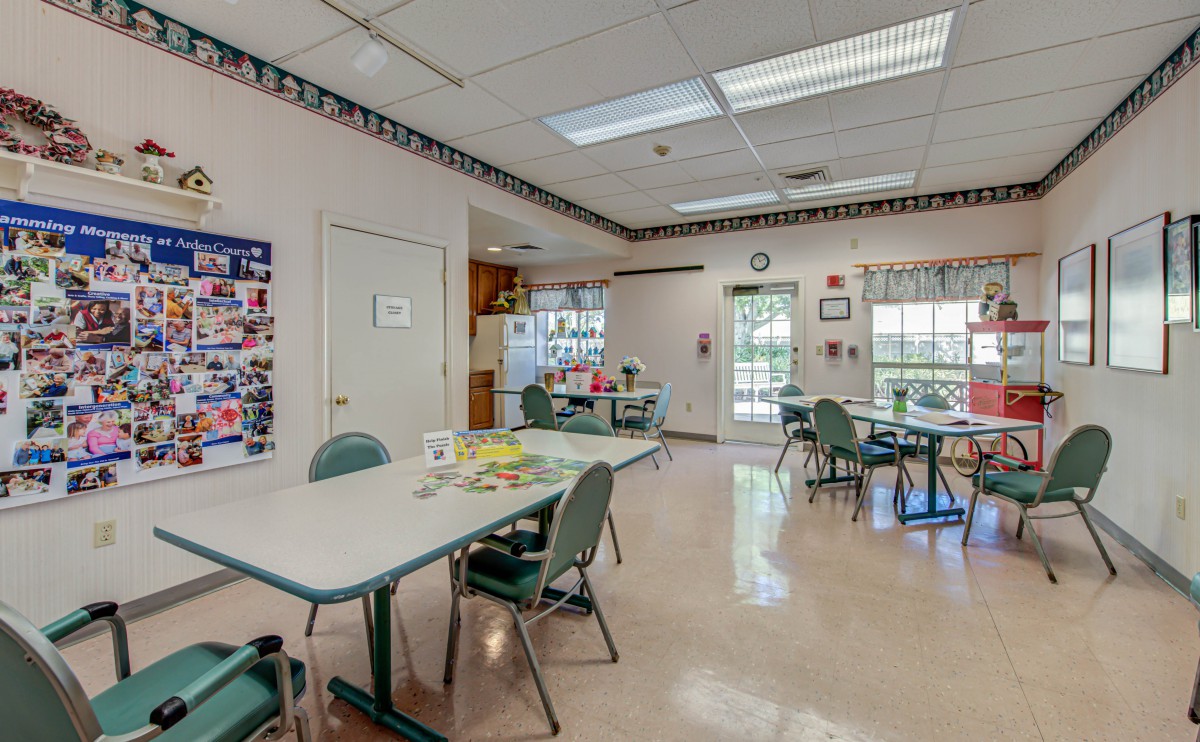 A well-lit classroom with tables and chairs, featuring craft supplies and art on the walls.