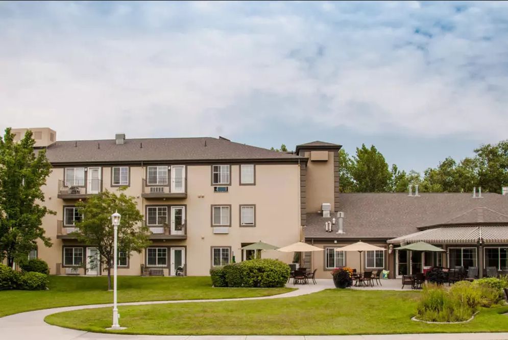 A view of a residential building with an outdoor patio and a well-maintained lawn.