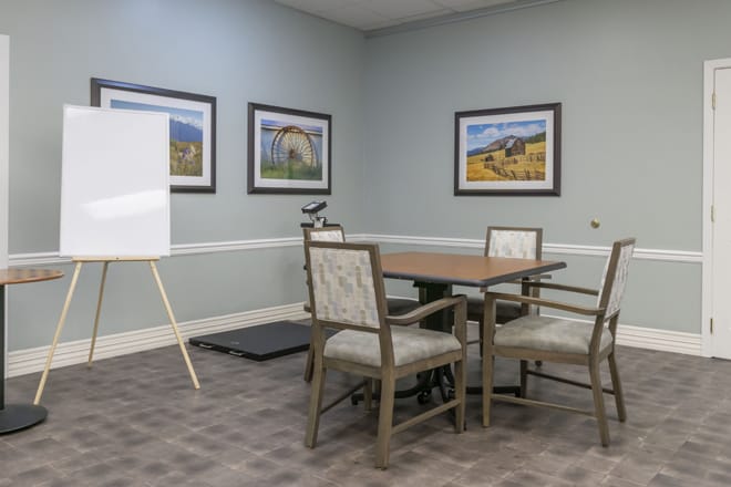 A small meeting room with a conference table, chairs, and a whiteboard.