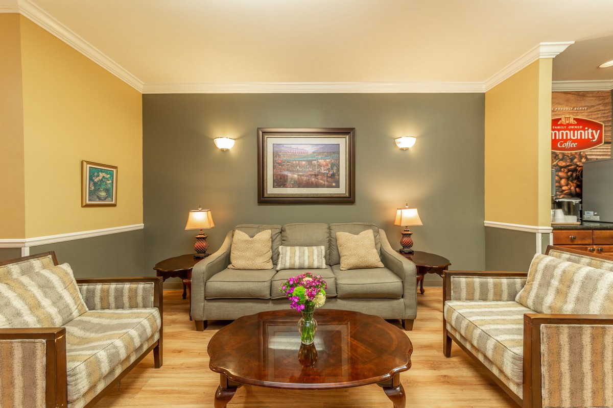 A cozy living room with classic furniture, featuring a sofa, coffee table, side tables with lamps, and wall art.