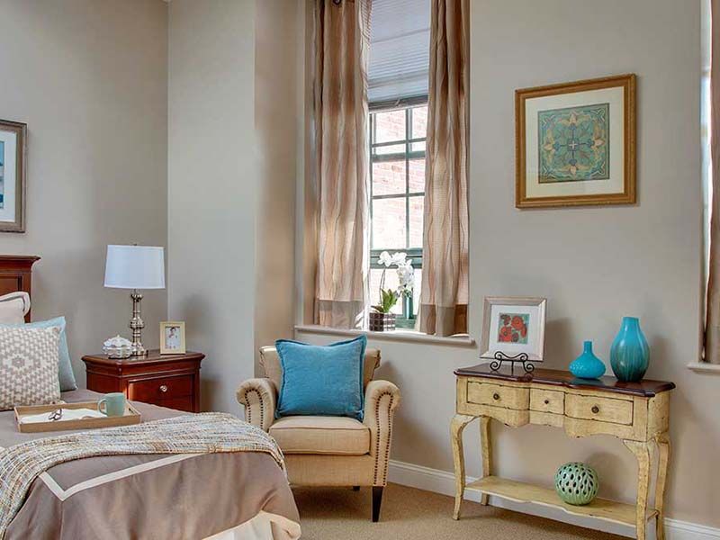 A cozy bedroom featuring an elegant armchair, soft curtains, and tasteful decor.