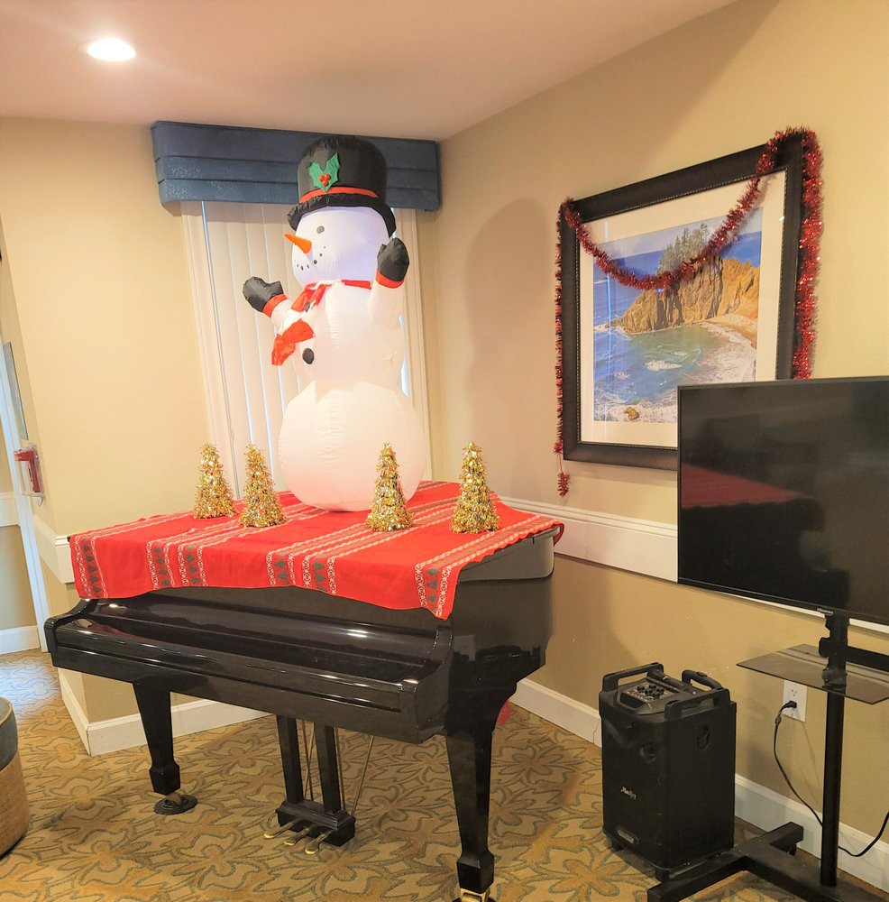 A festive room with a snowman decoration on top of a piano.