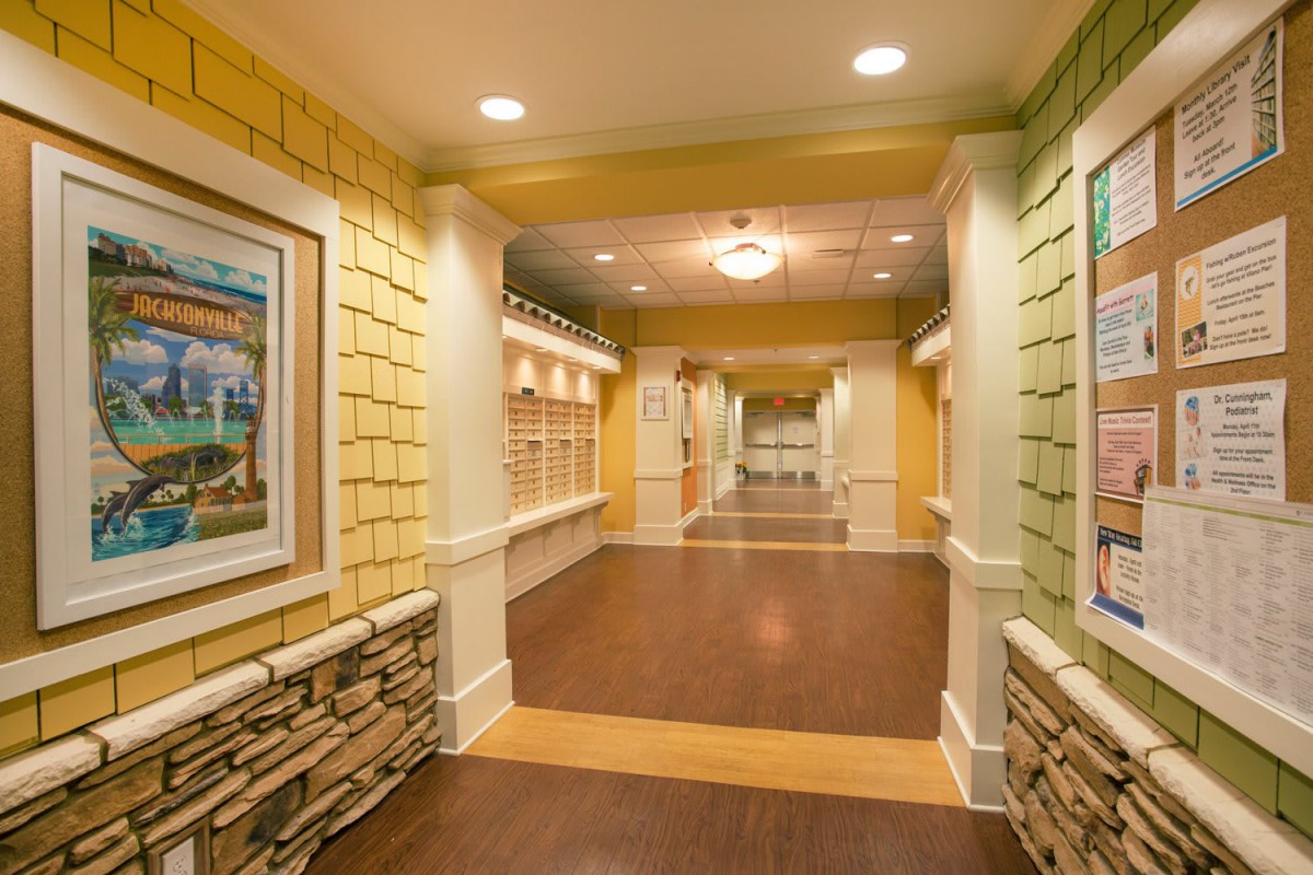 A warmly lit hallway featuring detailed interior design with artwork and wood flooring.