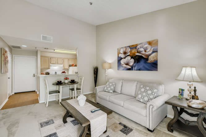 A modern living room featuring a comfortable sofa, stylish coffee table, and a scenic view of the adjacent kitchen and dining area.